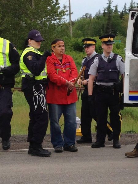 Ron Tremblay, holding sacred pipe, is arrested. Photo courtesy of @1tnb