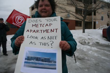 ACORN Nova Scotia member and MetCap tenant Lisa Fairn. The sign includes a photo of what ACORN believes to be the three-garage home of MetCap property manager Teddy Zaghloul. Photo Robert Devet