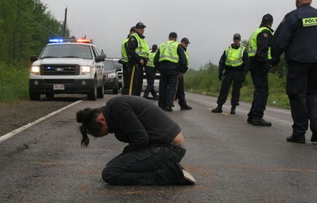 Susanne Patles in prayer, as New Brunswick RCMP confer. [Photo: M. Howe]