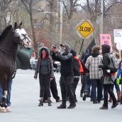 A masked protester photographs a police officer