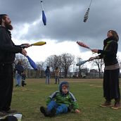 A boy summersaults through an arch made by these two jugglers.