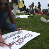 One protester finishes her sign at the commons before joining the march (Photo: Hilary Beaumont)