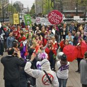 The march gathers at Grand Parade, outside City Hall, to rally. While the organizers set up the stage, the protesters began to sing softly in unison "All we are saying, is give food a chance."